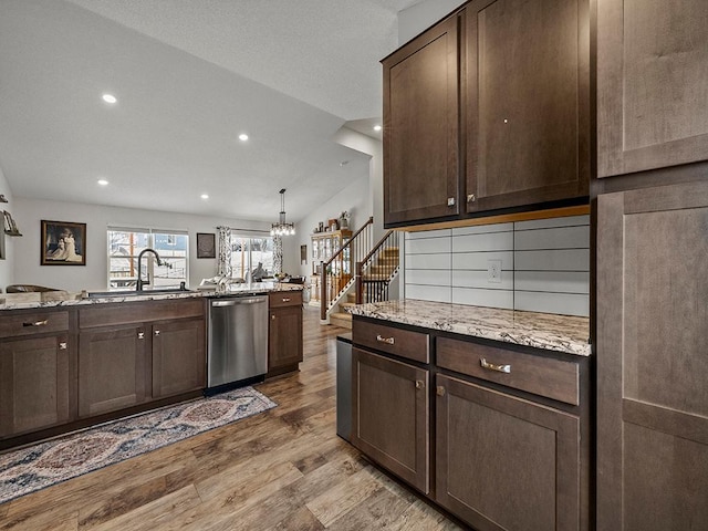 kitchen with pendant lighting, dishwasher, light stone counters, dark brown cabinets, and light hardwood / wood-style flooring