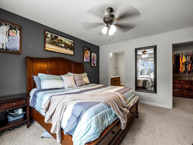 bedroom featuring a walk in closet, light carpet, a closet, and a textured ceiling