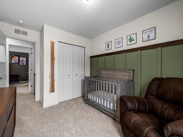 carpeted bedroom featuring a textured ceiling and a closet