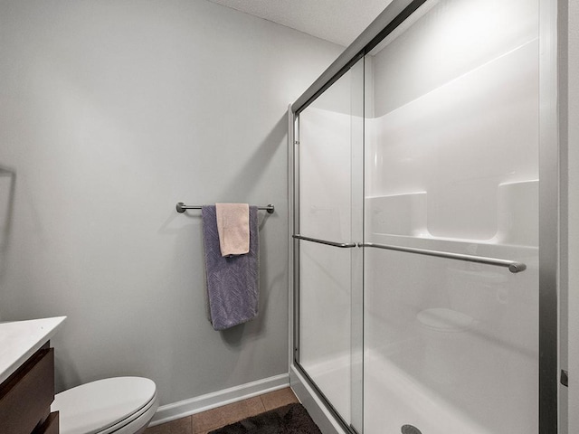 bathroom featuring vanity, tile patterned floors, a shower with door, and toilet