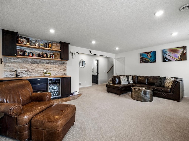 living room with wine cooler, light colored carpet, bar area, and a textured ceiling