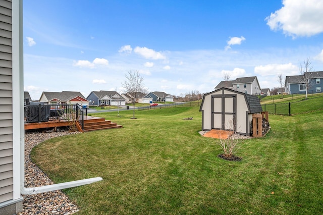 view of yard with a fenced backyard, an outdoor structure, a wooden deck, a residential view, and a storage unit