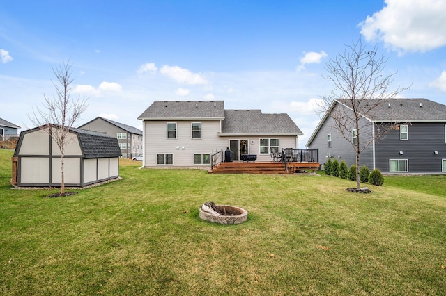 rear view of property with an outbuilding, a lawn, an outdoor fire pit, a deck, and a shed