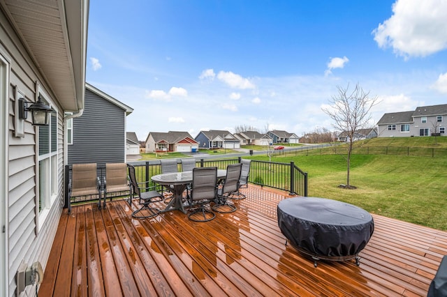 deck featuring outdoor dining area, a lawn, a fenced backyard, and a residential view