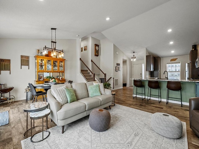 living room featuring recessed lighting, light wood-style flooring, vaulted ceiling, baseboards, and stairs