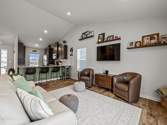 living area featuring dark wood-type flooring, lofted ceiling, and baseboards