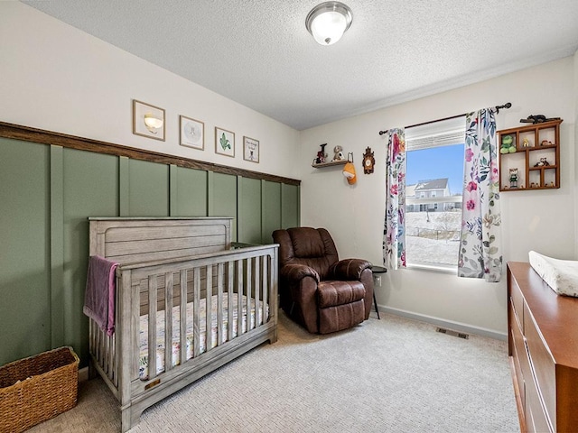 bedroom with baseboards, light colored carpet, visible vents, and a textured ceiling