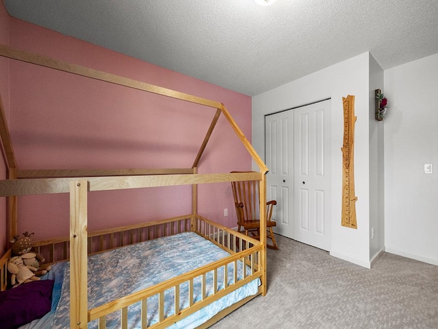 carpeted bedroom with a closet, baseboards, and a textured ceiling