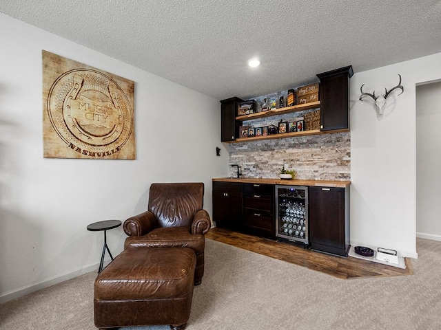 bar featuring beverage cooler, indoor bar, carpet flooring, and baseboards