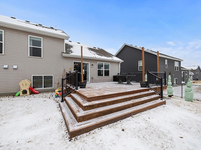 snow covered back of property featuring fence and a wooden deck