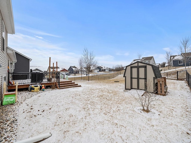 view of yard featuring a residential view, a fenced backyard, a wooden deck, and a storage unit