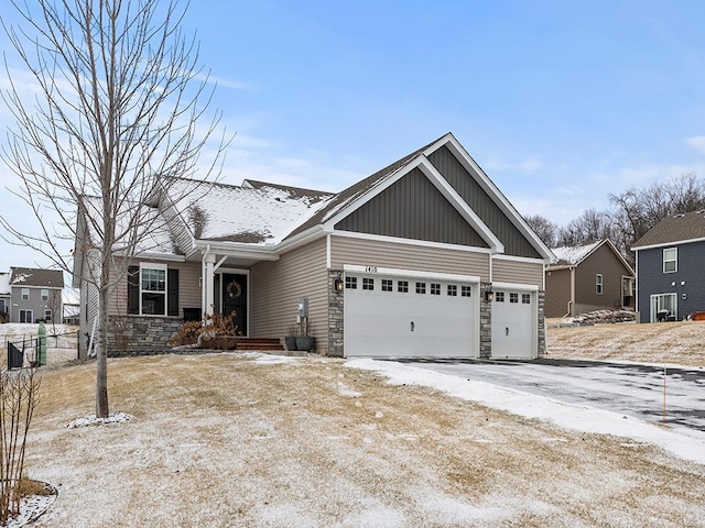 craftsman-style house featuring aphalt driveway, stone siding, and an attached garage