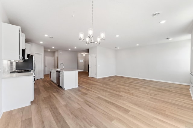 kitchen with light hardwood / wood-style flooring, appliances with stainless steel finishes, an island with sink, pendant lighting, and white cabinets