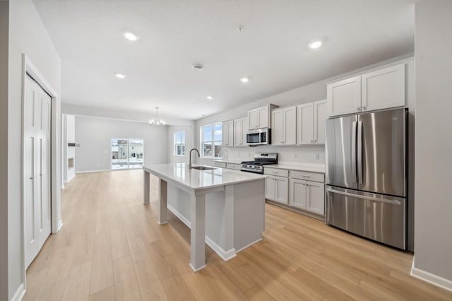 kitchen with stainless steel appliances, backsplash, light wood-type flooring, and light countertops