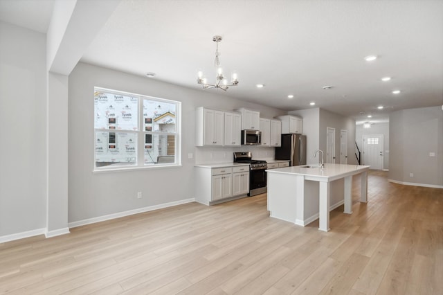 kitchen featuring stainless steel appliances, light wood-type flooring, a sink, and baseboards