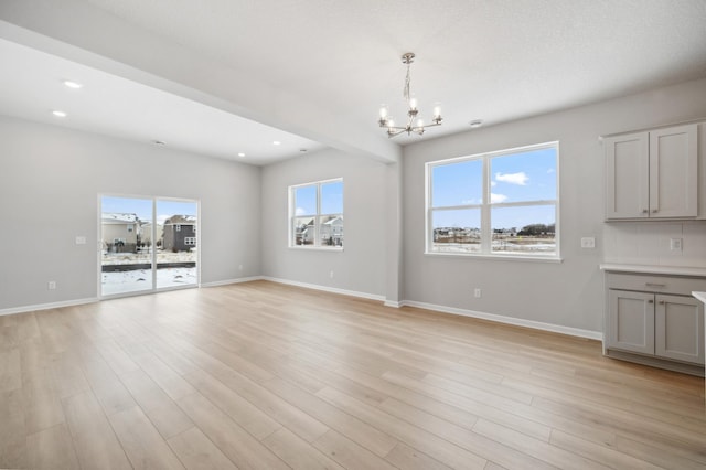 unfurnished dining area with recessed lighting, a notable chandelier, light wood-style flooring, and baseboards