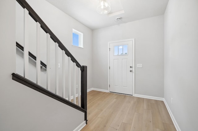 entrance foyer featuring light wood-type flooring, baseboards, and stairway