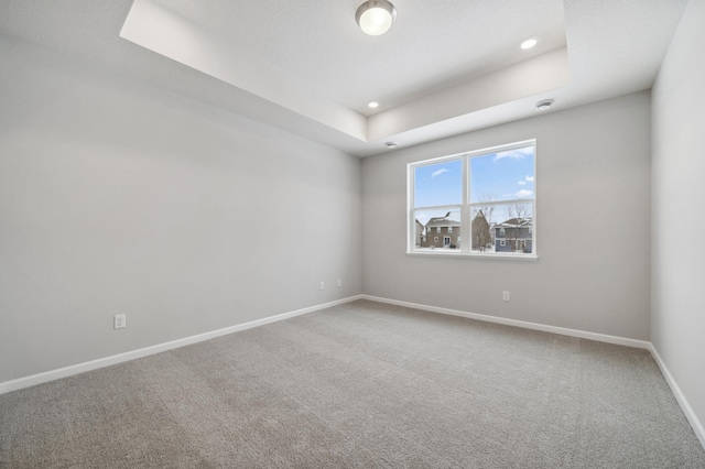 carpeted spare room featuring baseboards, a tray ceiling, and recessed lighting