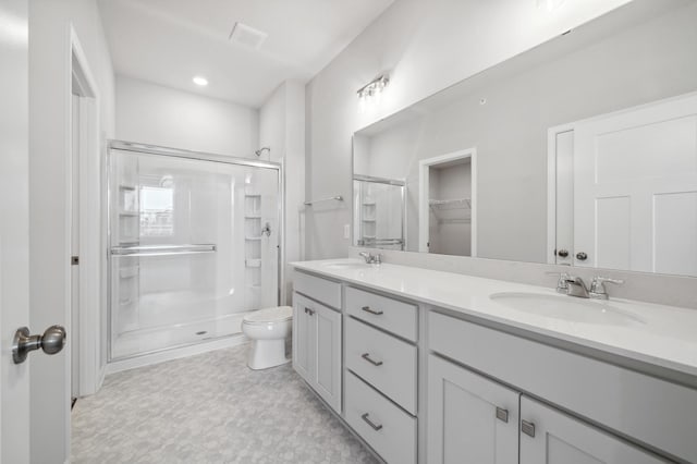 full bathroom with toilet, a stall shower, double vanity, and a sink