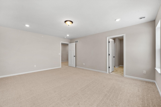 spare room featuring light carpet, recessed lighting, visible vents, and baseboards