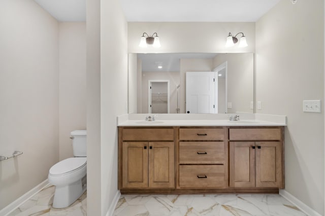 full bath featuring double vanity, baseboards, toilet, marble finish floor, and a sink