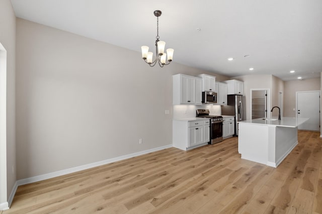 kitchen featuring appliances with stainless steel finishes, white cabinetry, light wood-style flooring, and baseboards