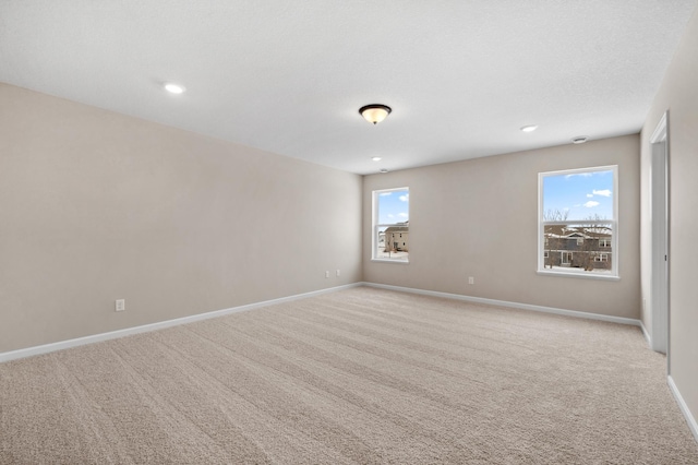 empty room with light carpet, baseboards, a textured ceiling, and recessed lighting