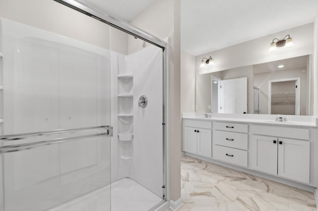 bathroom with marble finish floor, a sink, and a shower stall