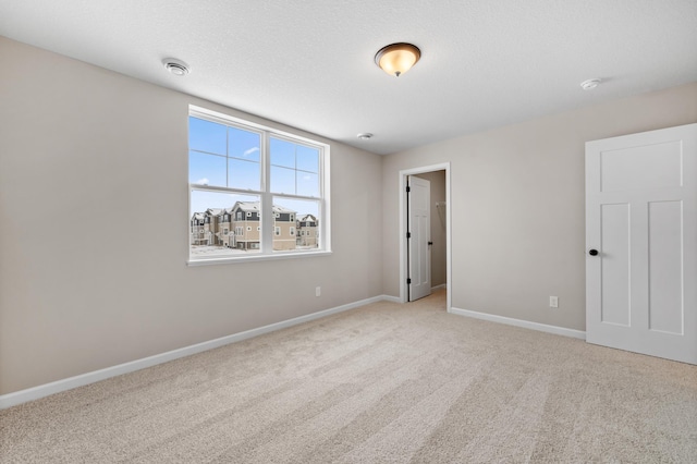 carpeted empty room with a textured ceiling and baseboards