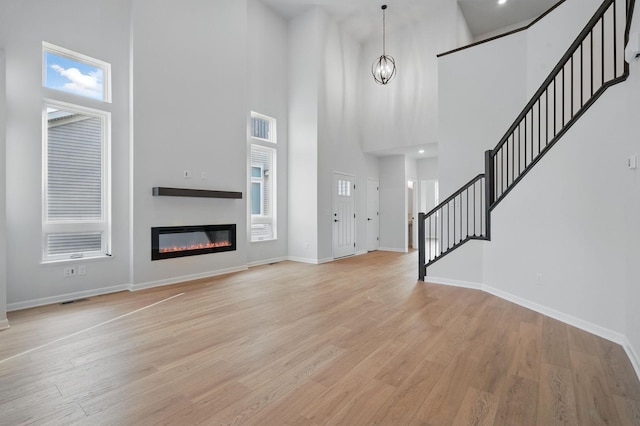 6566 Jody Ave S, Cottage Grove, MN 55016 - foyer entrance with a towering ceiling, stairway, baseboards, a glass covered fireplace, and light wood-style floors