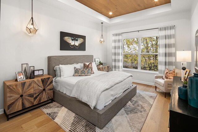 bedroom with a tray ceiling, light wood finished floors, recessed lighting, wood ceiling, and baseboards