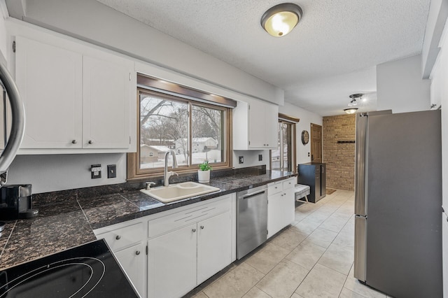 kitchen featuring sink, stainless steel appliances, a textured ceiling, white cabinets, and light tile patterned flooring