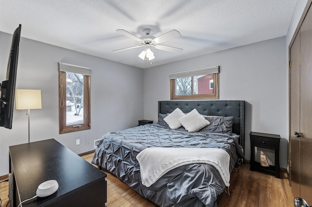 bedroom featuring hardwood / wood-style flooring, ceiling fan, and a textured ceiling