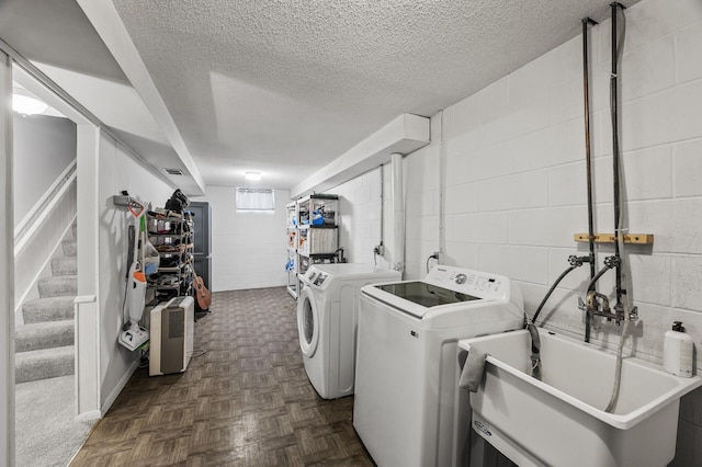 laundry area with sink, dark parquet floors, a textured ceiling, and washer and clothes dryer