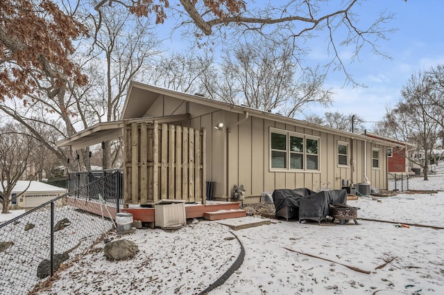 snow covered house featuring central AC unit