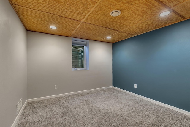 carpeted empty room featuring wood ceiling