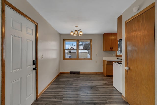 kitchen with dark hardwood / wood-style floors, white range with gas stovetop, an inviting chandelier, and decorative light fixtures