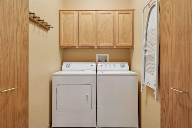 clothes washing area featuring cabinets and washing machine and clothes dryer