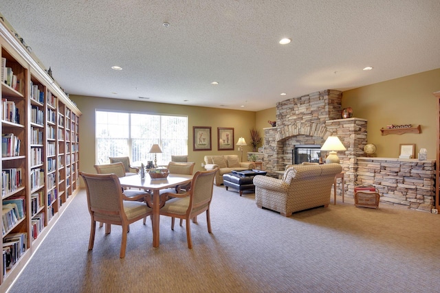 carpeted dining space featuring a stone fireplace and a textured ceiling