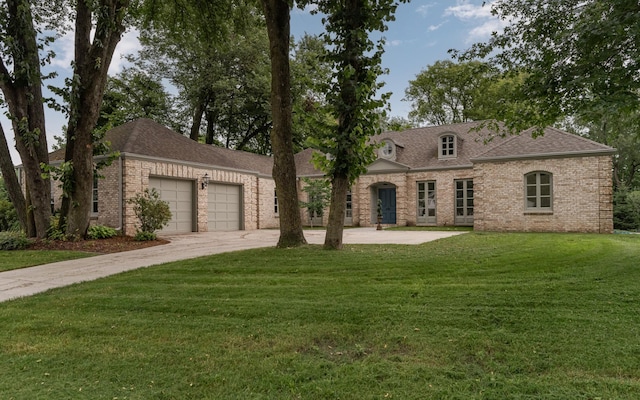 french provincial home featuring concrete driveway, roof with shingles, an attached garage, a front lawn, and brick siding