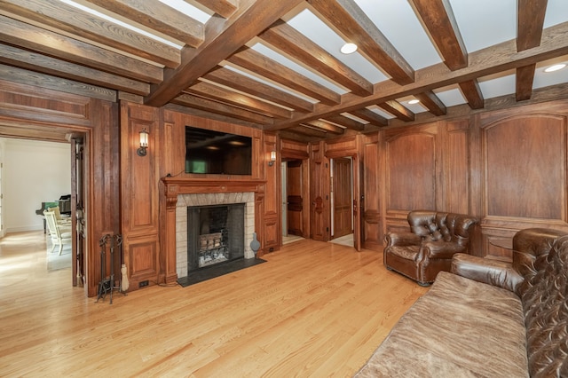 living room with beam ceiling, wooden walls, and light wood finished floors