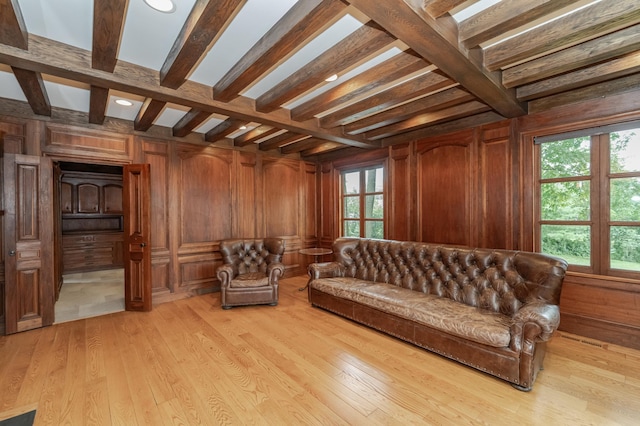 sitting room featuring beamed ceiling, wooden walls, and light wood finished floors