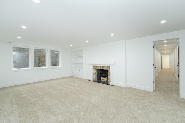 unfurnished living room featuring built in features, a fireplace, recessed lighting, light colored carpet, and baseboards