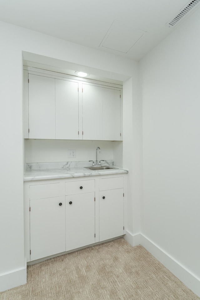 bar featuring light colored carpet, visible vents, a sink, and baseboards