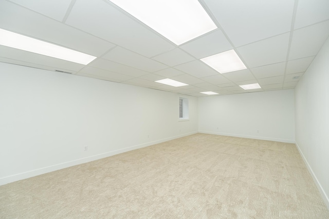 empty room featuring light carpet, visible vents, baseboards, and a drop ceiling