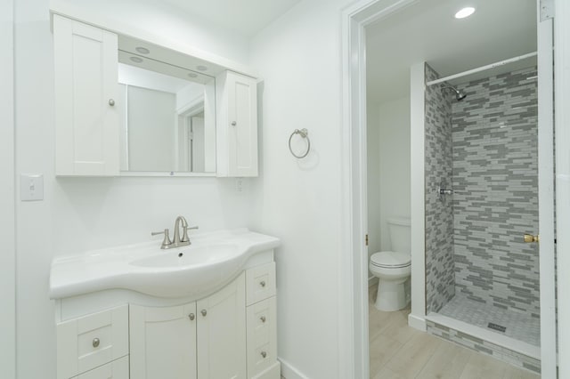 full bath featuring wood finished floors, a stall shower, vanity, and toilet