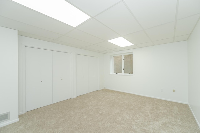 basement with baseboards, a drop ceiling, visible vents, and light colored carpet