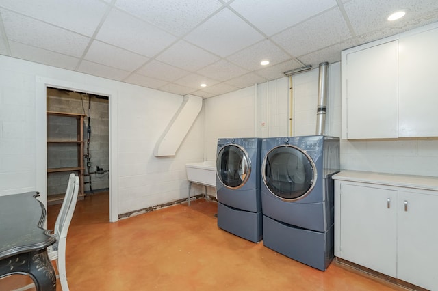 laundry room with concrete block wall, cabinet space, washer and clothes dryer, and recessed lighting