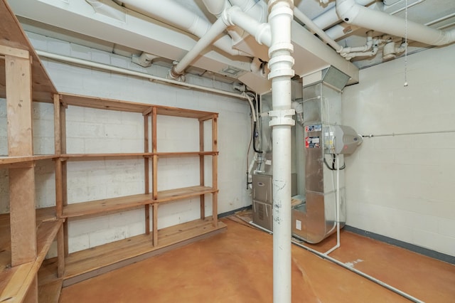 unfinished basement featuring concrete block wall and heating unit