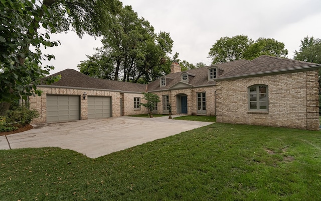 french country style house featuring an attached garage, brick siding, driveway, a front lawn, and a chimney